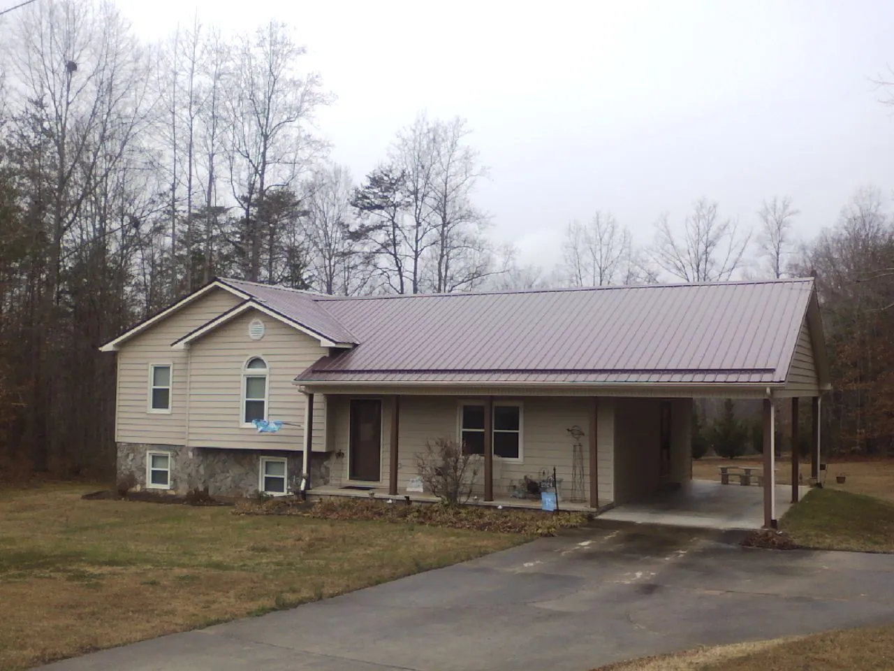 Burgundy metal roof on a tan split level home with an attached carport in Hobe Sound