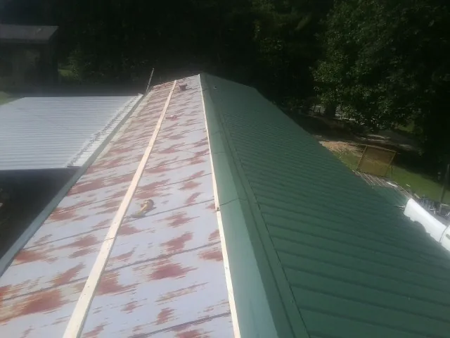 Old rusted panels beside newly installed green metal roofing — Wind Damage Roof Repair by Roofing Brothers in Hobe Sound