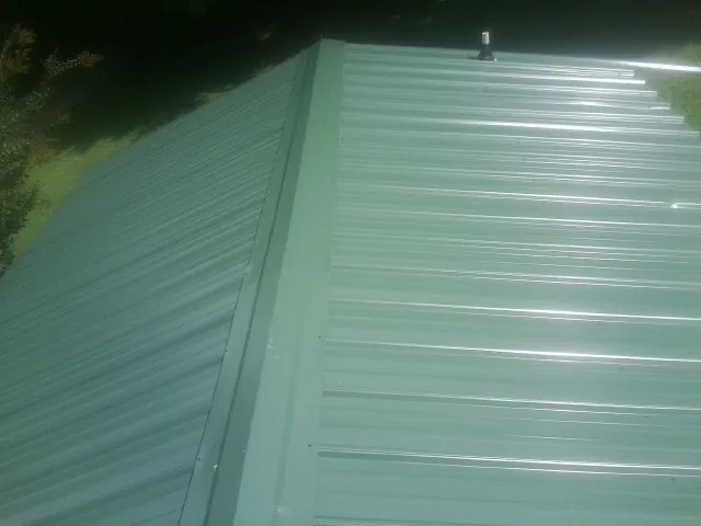 New green metal panels meeting at the ridge of a roof — Flat Roof Repair work by our crew in Hobe Sound