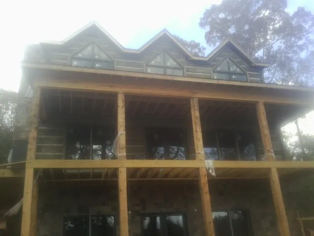Dormers and porch framing on a large log home under construction — Roof Coating work by our crew in Hobe Sound