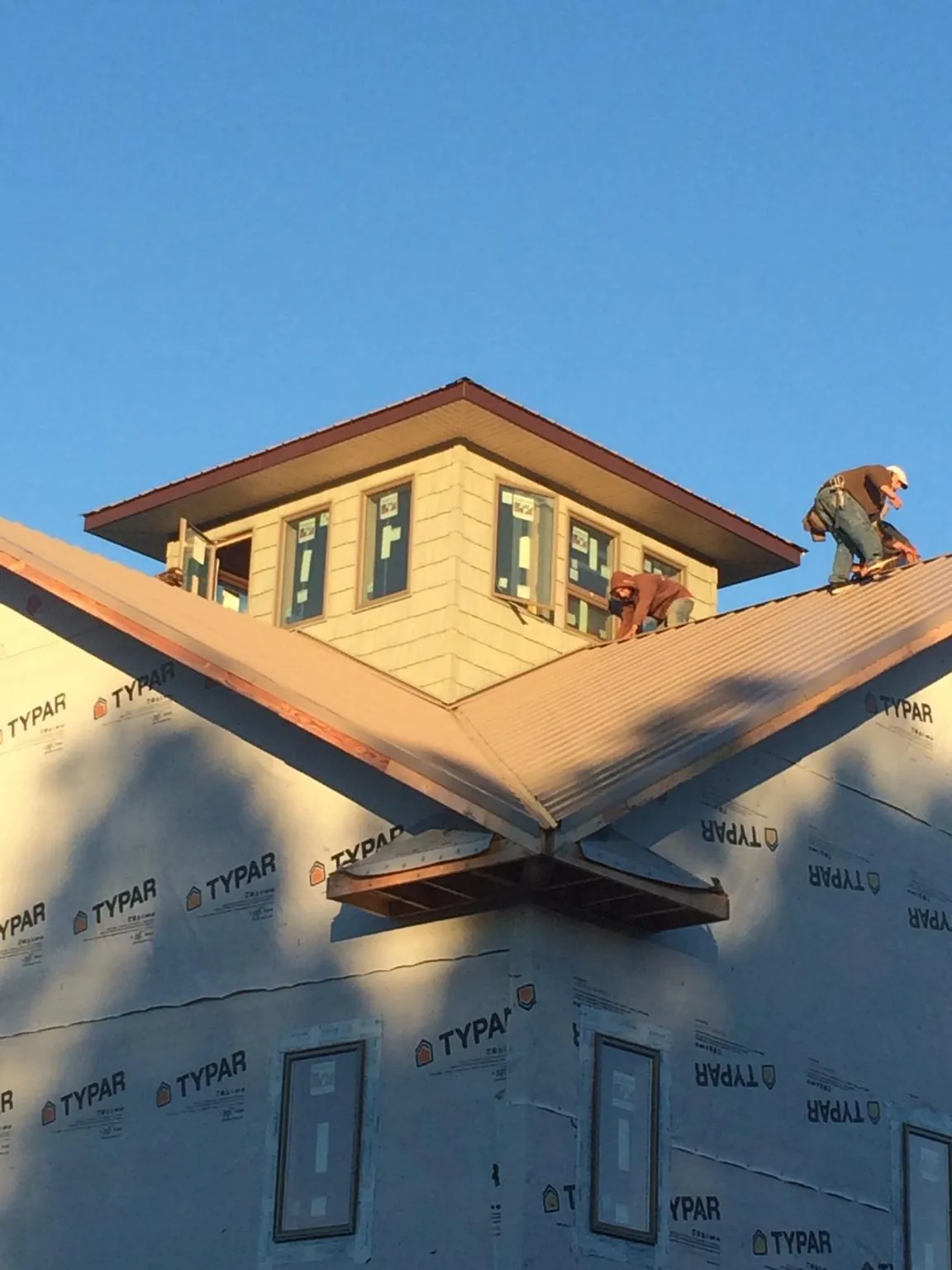 Roofers working around a rooftop cupola on a new metal roof at sunset — Roof Waterproofing in Hobe Sound by Roofing Brothers